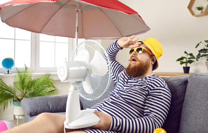 MAN MET VENTILATOR EN PARASOL IN WOONKAMER