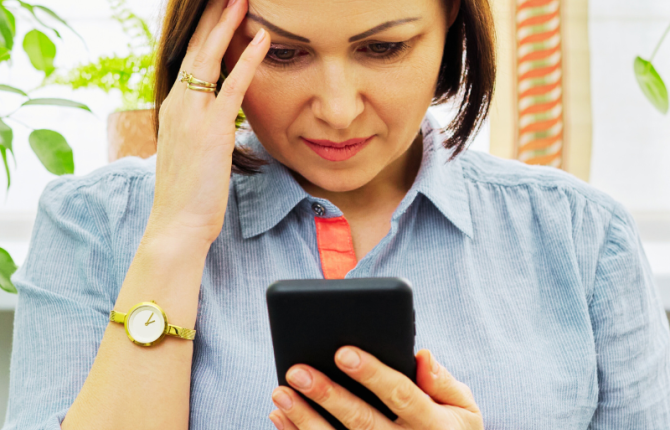 vrouw kijkt bedenkelijk naar telefoon